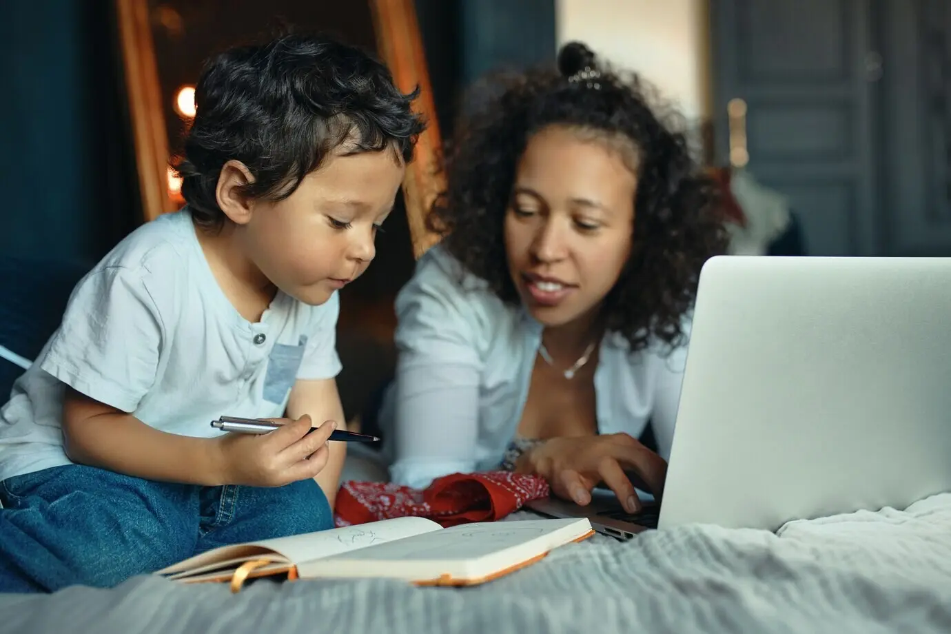 Раннее развитие, образование, детство и современные электронные гаджеты. Портрет заботливой молодой латиноамериканки на кровати, пользующейся ноутбуком.